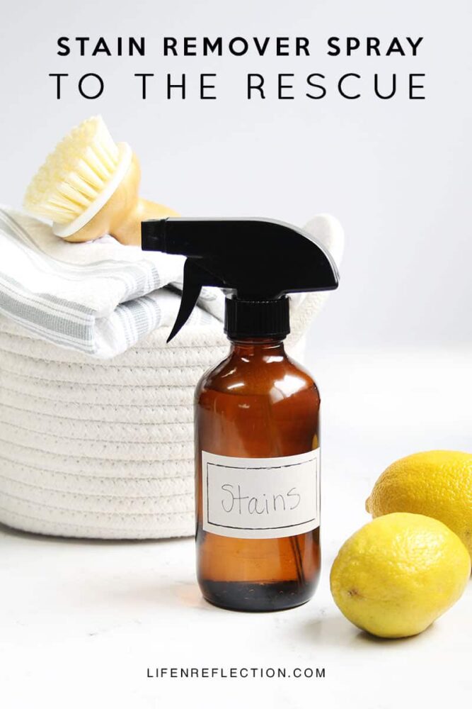 Amber glass spray bottle labeled stains next to yellow lemons and white woven laundry basket.