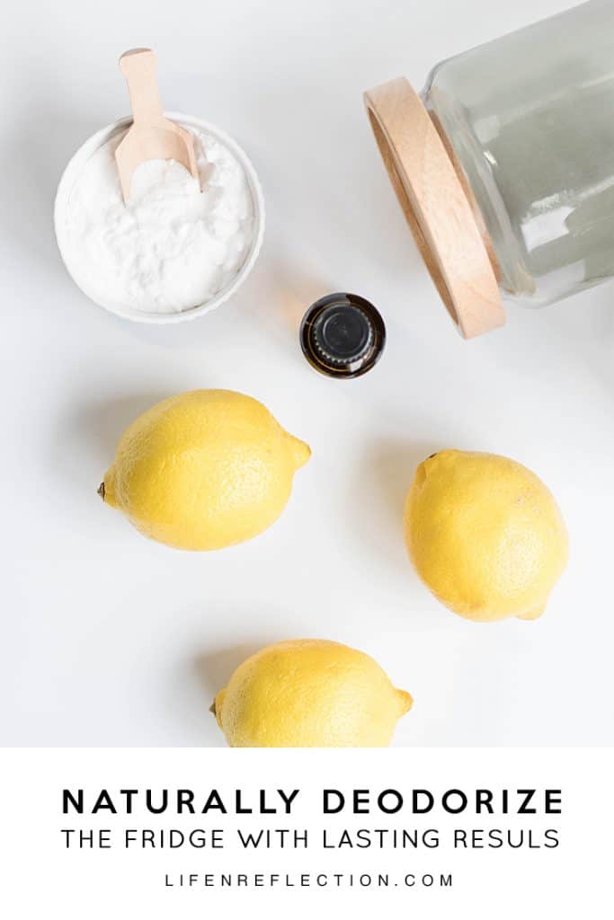 Looking down on a sun light white countertop into a bowl of baking soda with a wooden scoop, fresh yellow lemons and pantry jar.
