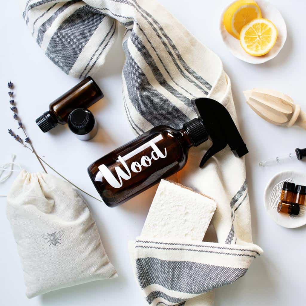 Natural cleaning supplies, fresh lemon slices, essential oil bottles, homemade cleaning solution, sponges, and towels.