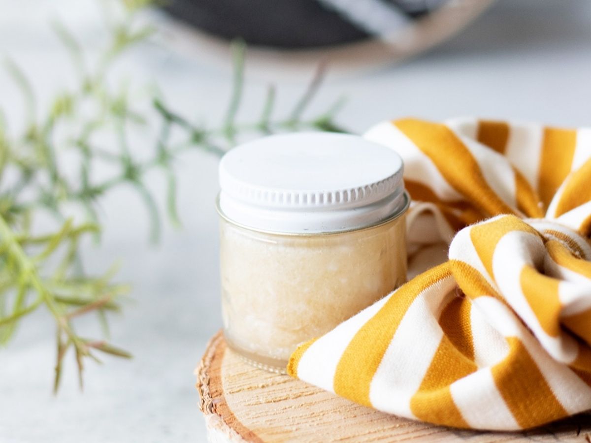 Small container of a DIY scalp scrub next a stripe hair box on a sunny bathroom counter.