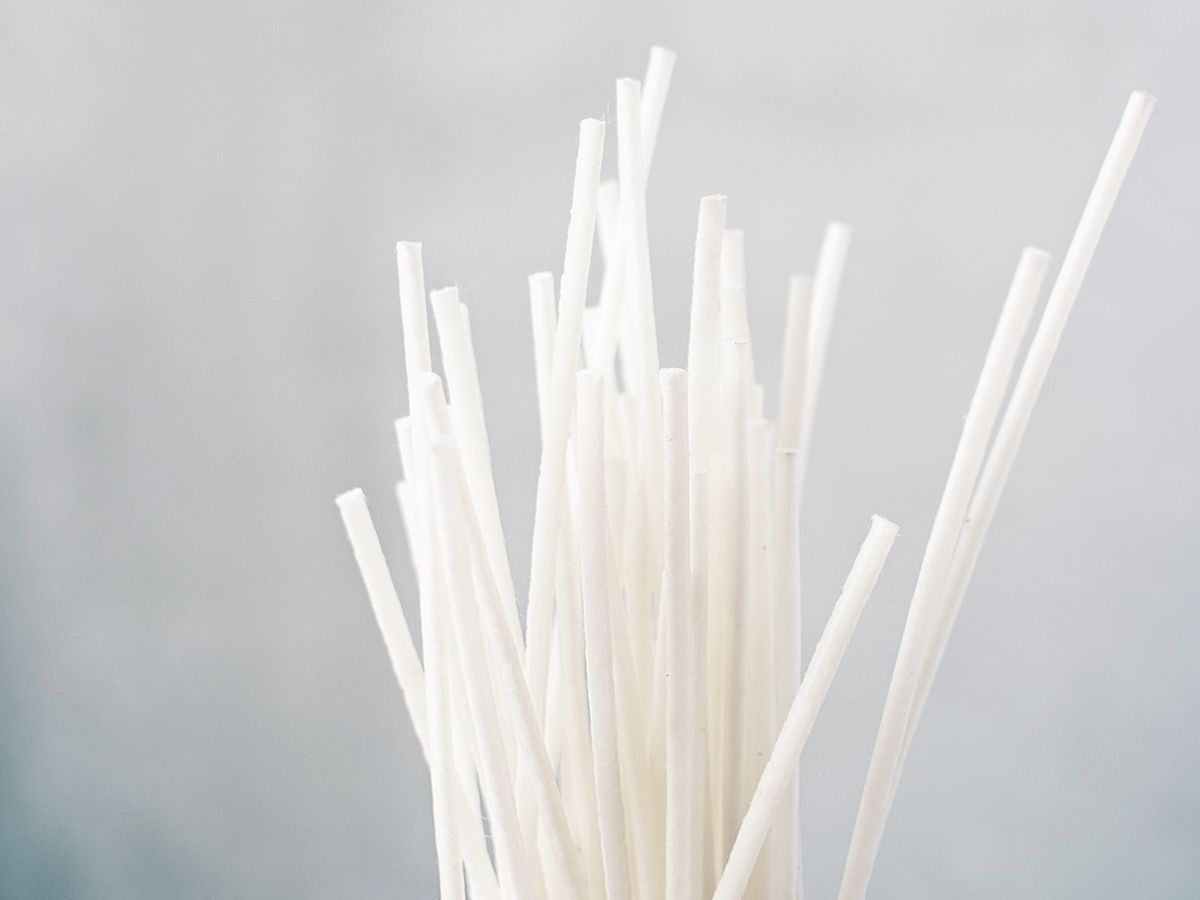 Bundle of white soy wax dipped cotton wicks on a blue grey background.