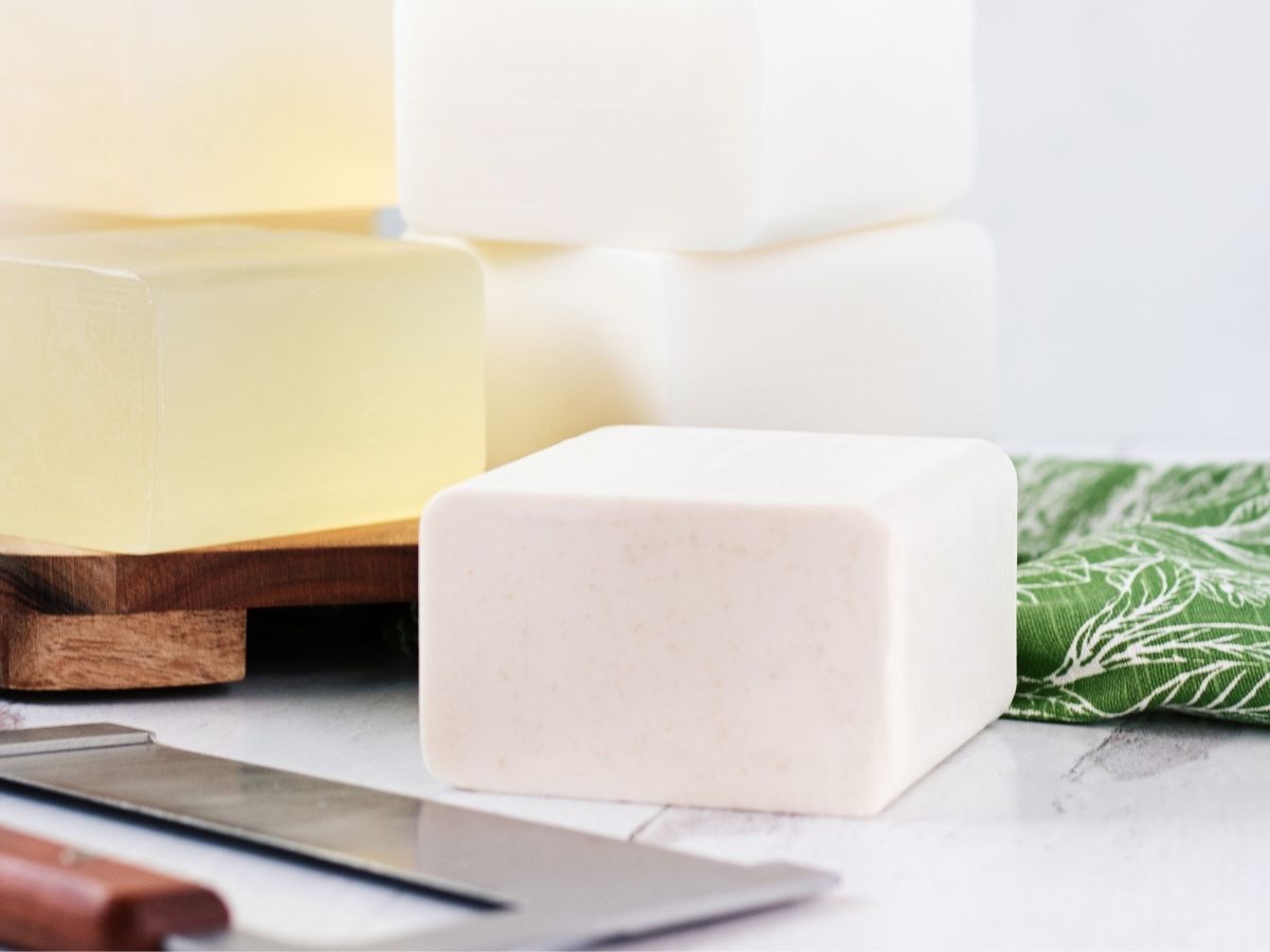 Blocks of melt and pour soap base stacked up on a wood cutting board