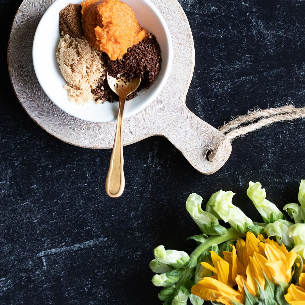 raw ingredients in a white bowl with a spoon for a lip scrub
