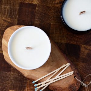 ceramic bowls filled with soy candle wax and wood wicks on dark wood background