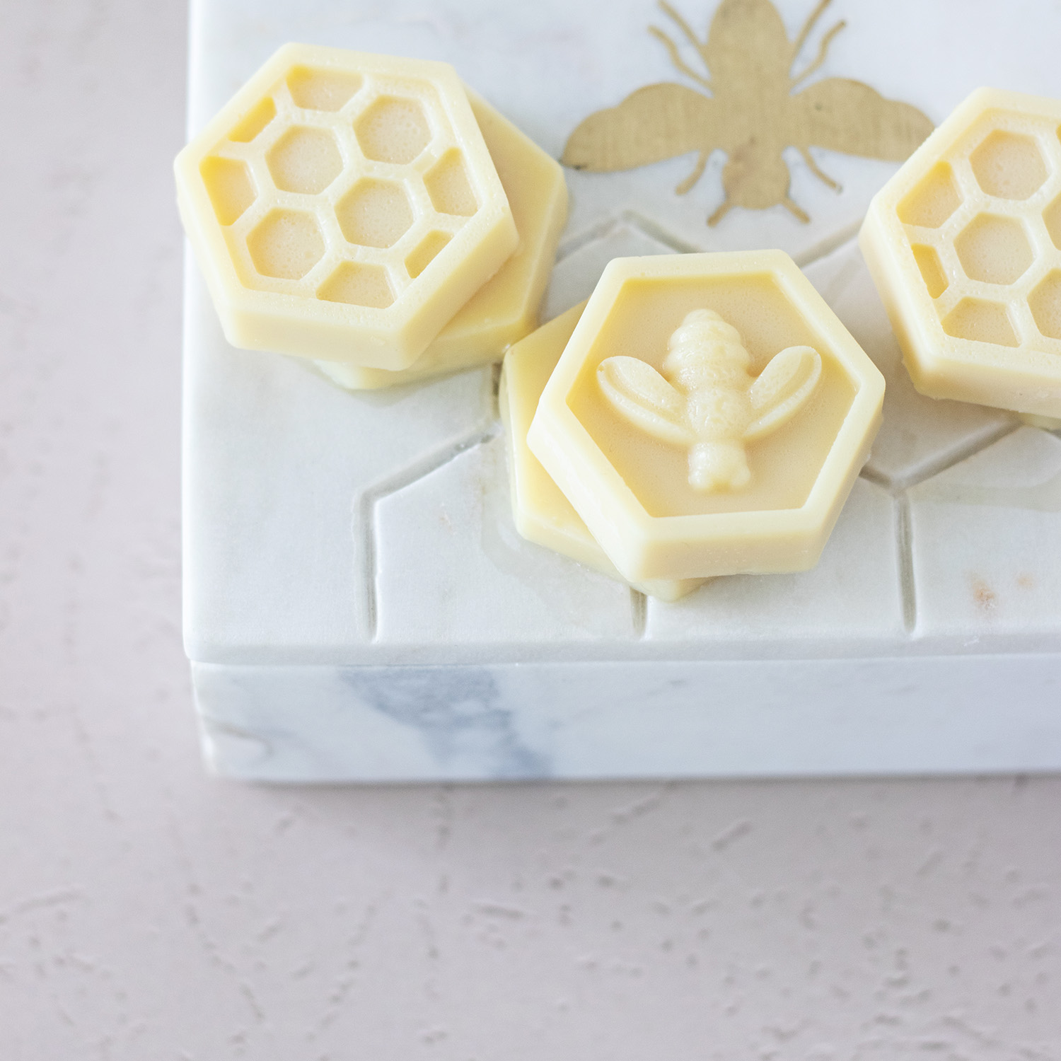 closeup of pastel yellow almond honey bath melts in hexagon shapes with honeycomb and bee patterns.