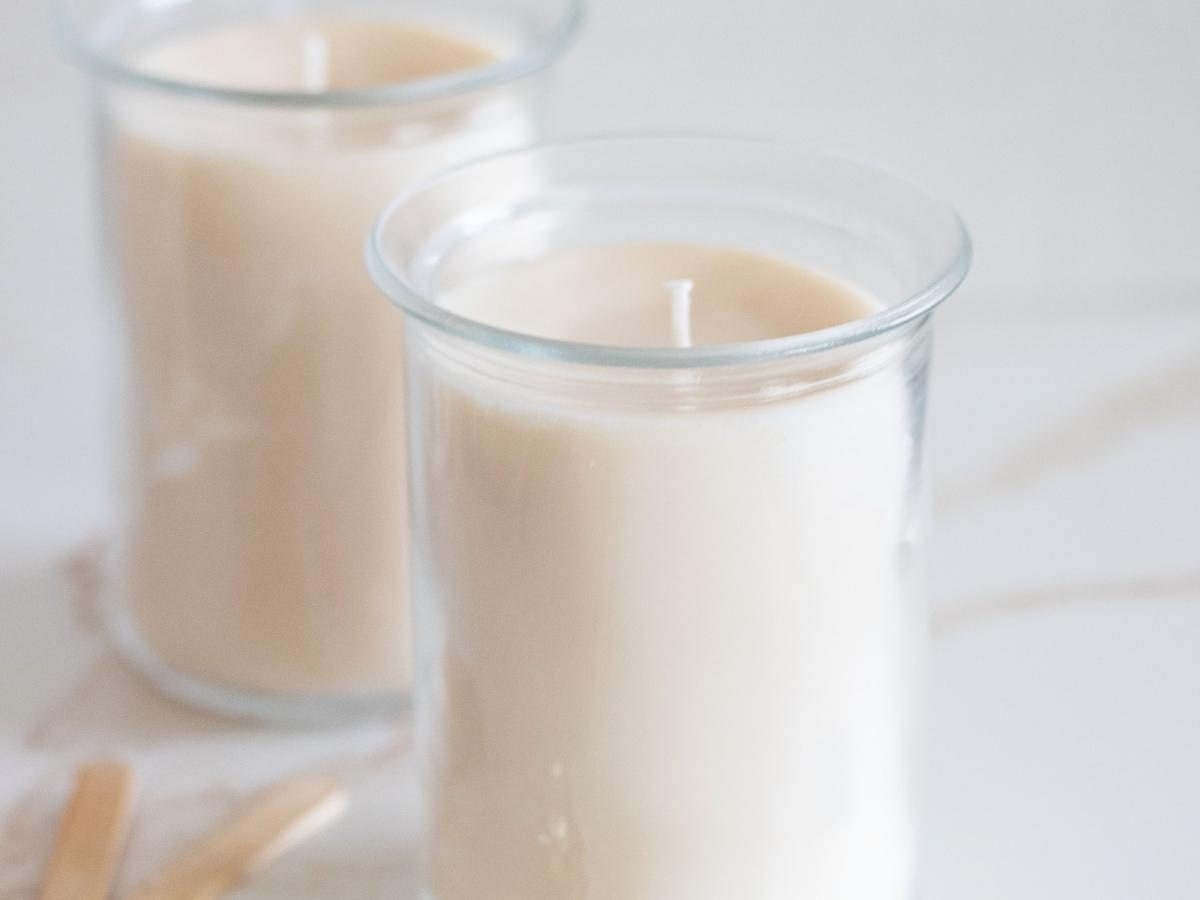 homemade scented candles in tall clear glass jars next to wick trimmer