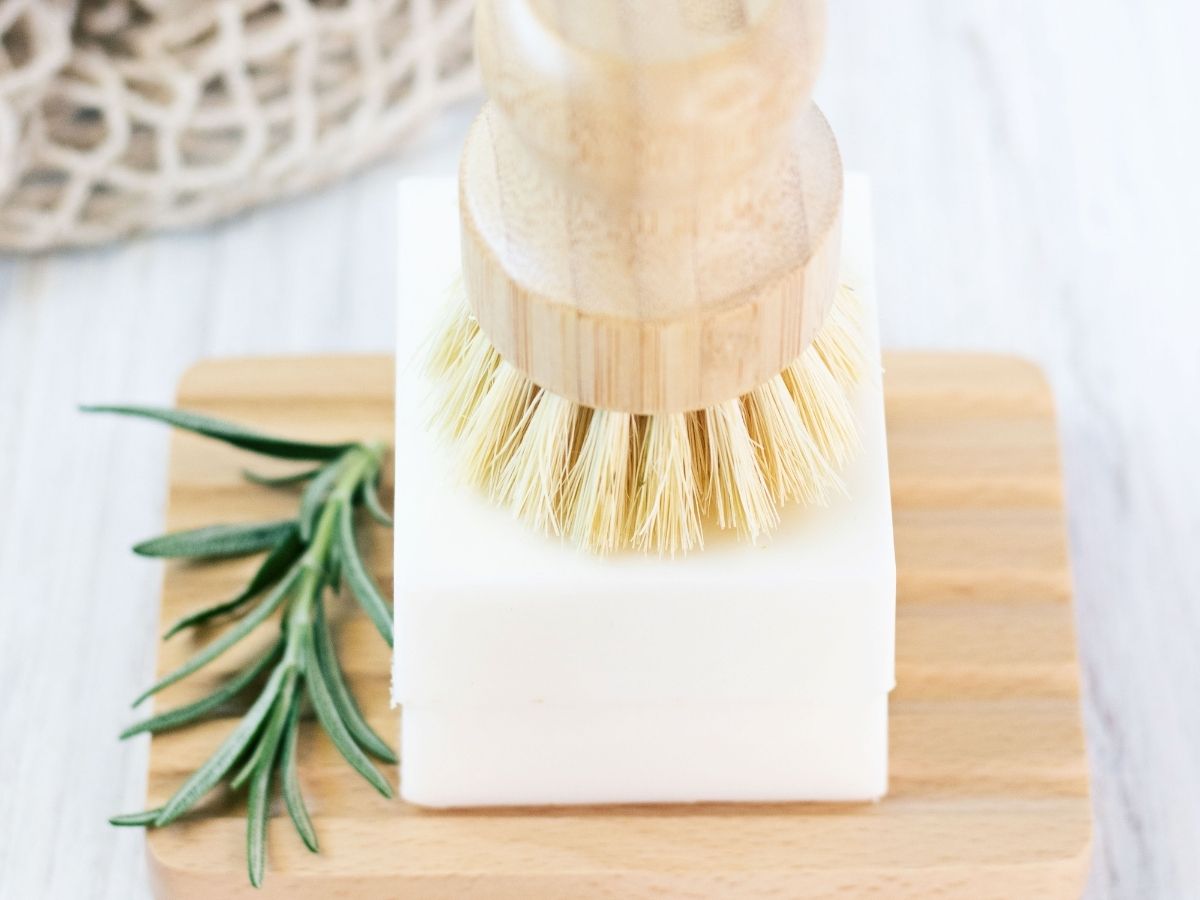 Double stack of solid dish soap bars under kitchen scrub brush on a bright kitchen counter.