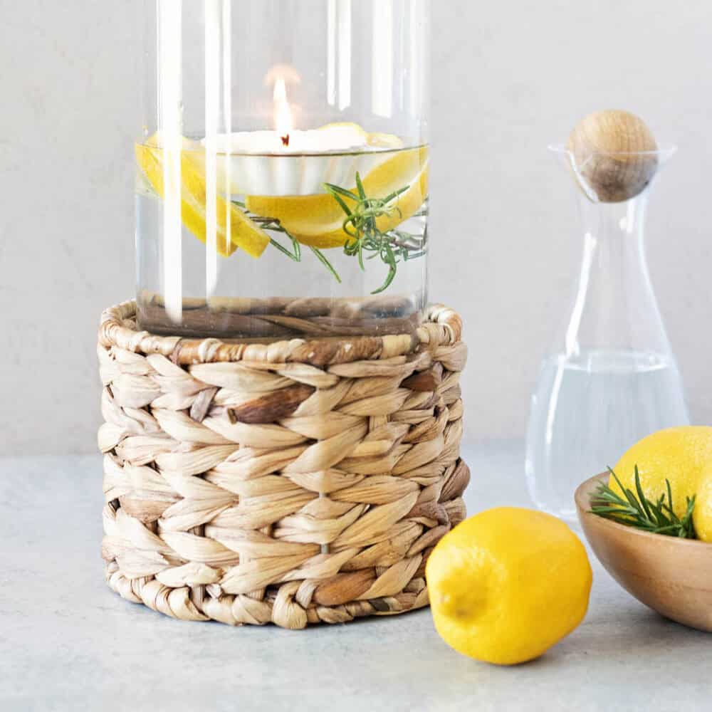 glowing floating candle in a large glass vessel with fresh lemon slices and rosemary