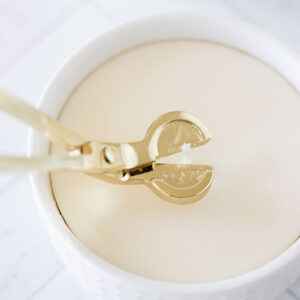 closeup of using a candle wick trimmer to cut a cotton wick