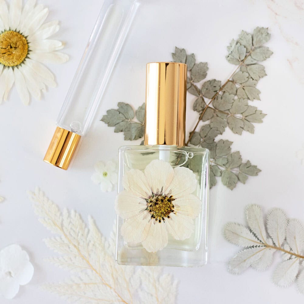 close up of glass perfume bottles with gold caps on top of pressed flowers