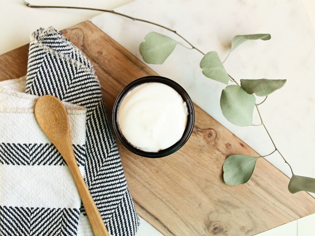 looking over an open amber glass jar filled with white handmade lotion
