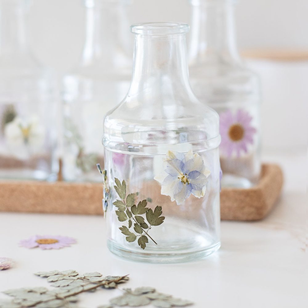 closeup of clear glass vases covered in pastel pressed flowers