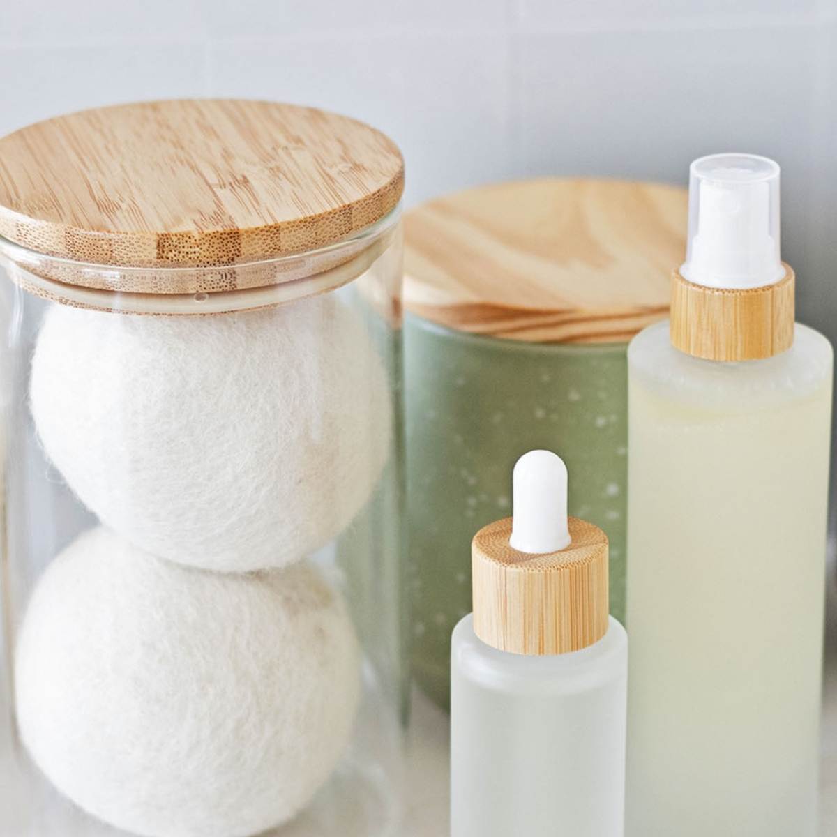 laundry room counter with a glass jar of wool dryer balls, wooden clothespins, and homemade bottles of linen spray and laundry scent booster.