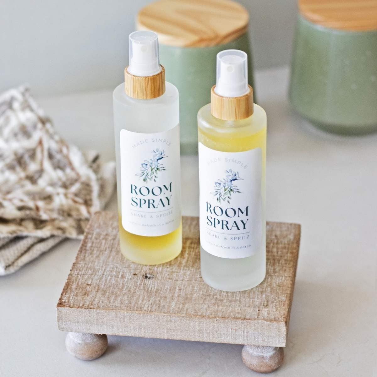 two bottles of room spray with DIY labels on a wood tray