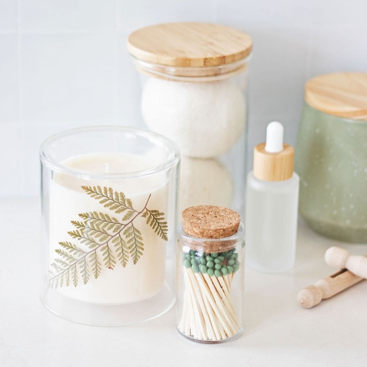 laundry counter with a soy wax candle, match jar, room spray bottle, clothespins, wool dryer balls, and jars