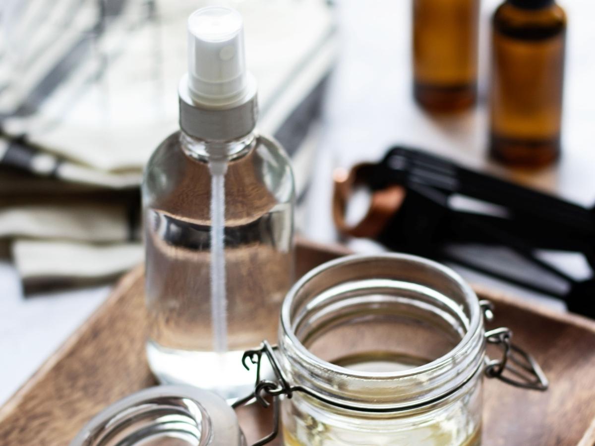 Glass jars and bottles with stainless steel cleaning solutions on a counter top.