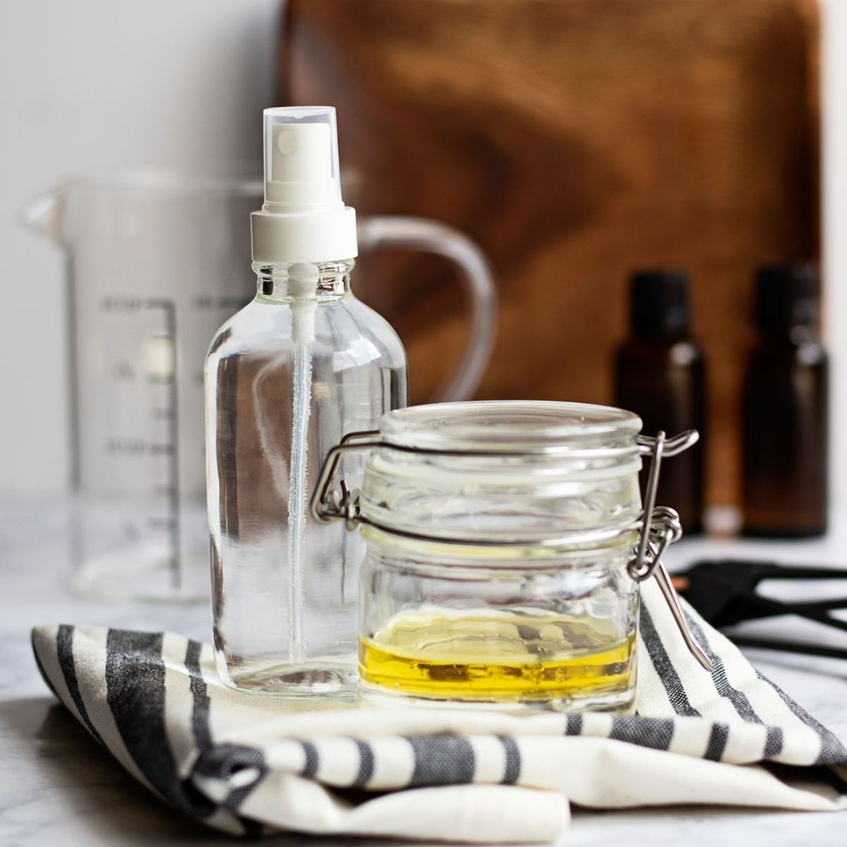 Glass jars and bottles with stainless steel cleaning solutions on a counter top.