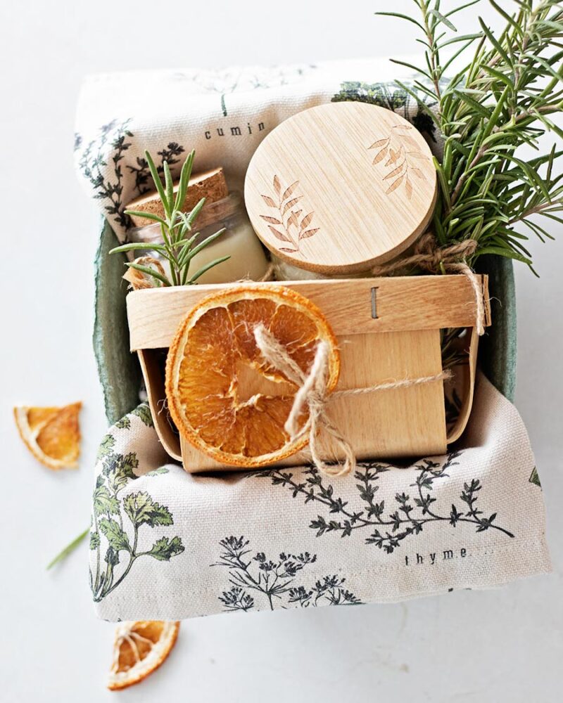 Fruit basket filled with handmade gifts for a gardener with a fresh bundle of rosemary and dried orange slices.