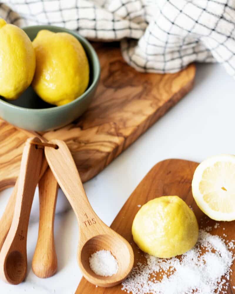 Natural wood cutting boards and measuring spoons with fresh lemons in a sunlight kitchen.