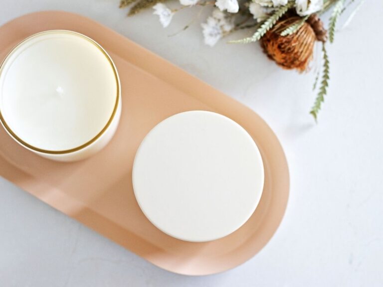 Looking over a tray of homemade candles on a white surface next to dried florals.