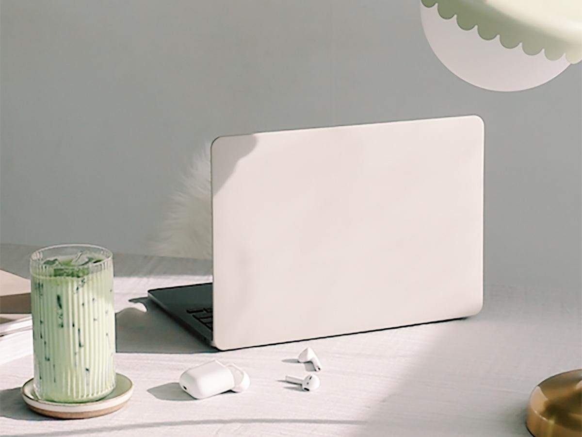 open laptop on desk under lamp next to a glass of green matcha