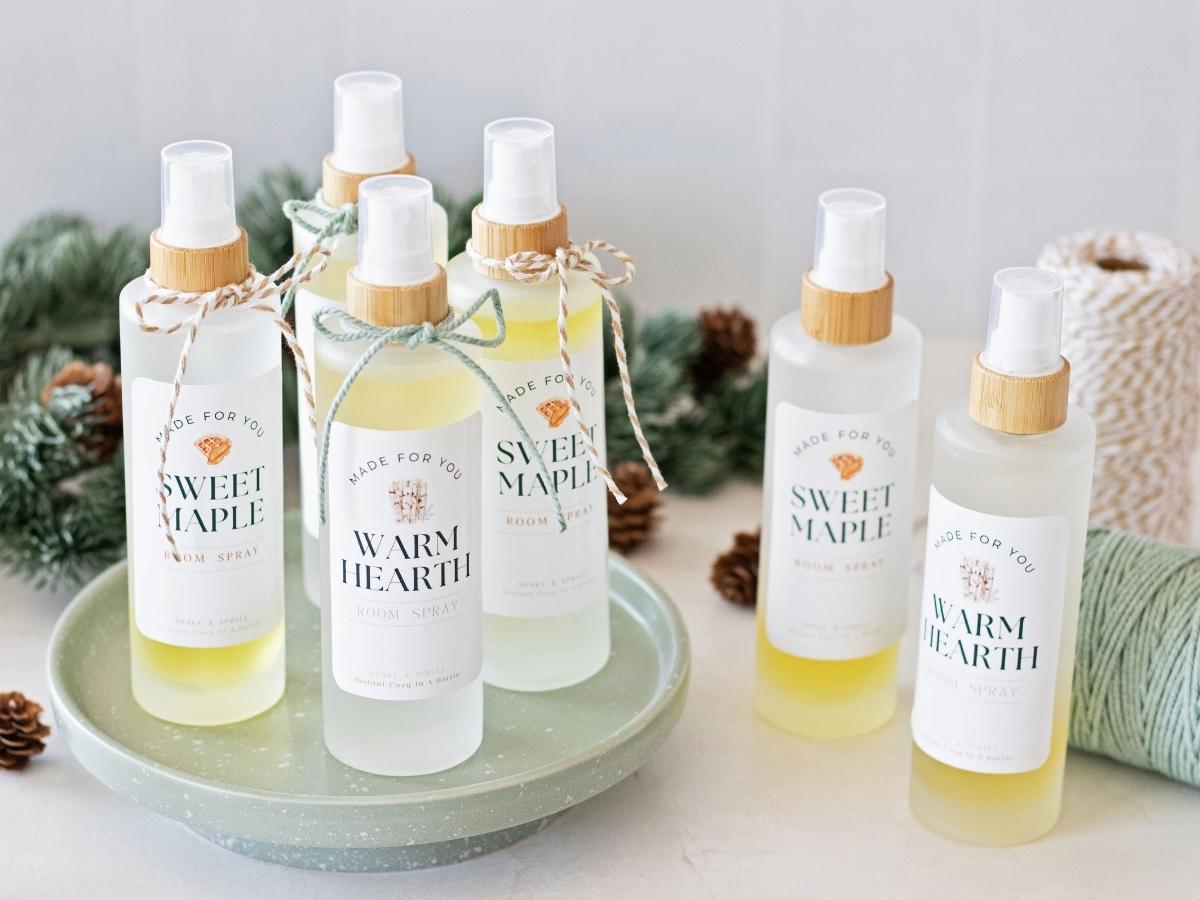 six frosted glass bottles of homemade room spray on light surface next to twine and pine cones